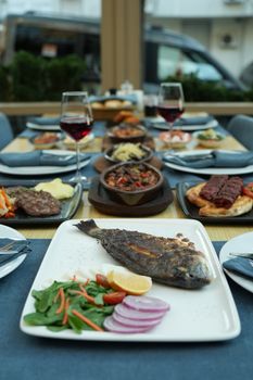 Grilled fish with vegetables on an elegant dining table set with wine, showcasing a delightful dining experience. - Fotografer Sidoarjo