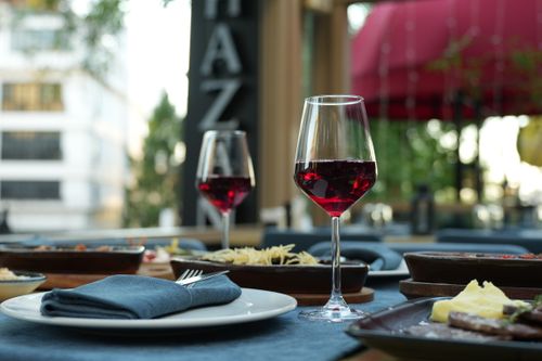 Free A sophisticated dining setup featuring red wine, gourmet dishes, and a casual outdoor atmosphere. Stock Photo