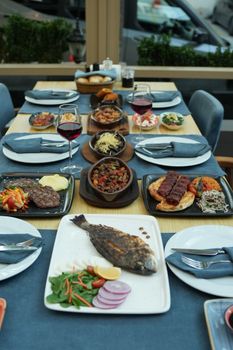 A luxurious dining table set with assorted gourmet dishes including grilled fish, steak, and sides.