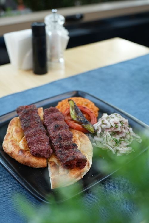 Free Appetizing platter with grilled kebabs, pita, salad, and grilled vegetables on a black plate. Stock Photo