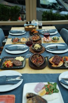 A beautifully presented dining table set with an array of gourmet dishes and glasses of wine in a restaurant setting.