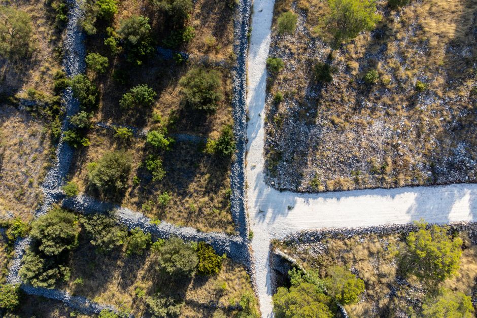 Aerial shot of a rocky landscape intersected by a white dirt path, showcasing natural terrain.