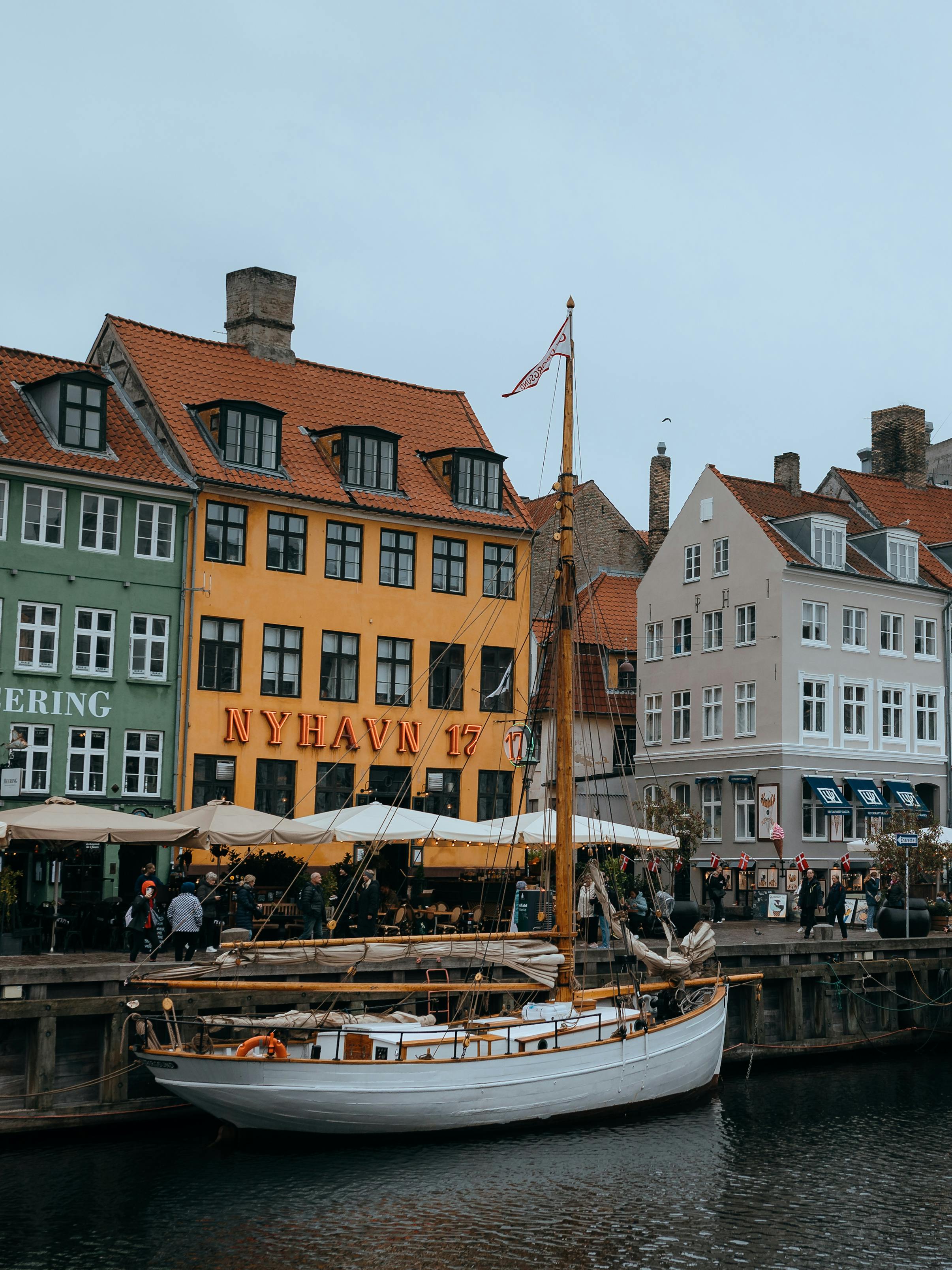 Colorful waterfront buildings and a classic boat in Nyhavn, Copenhagen.