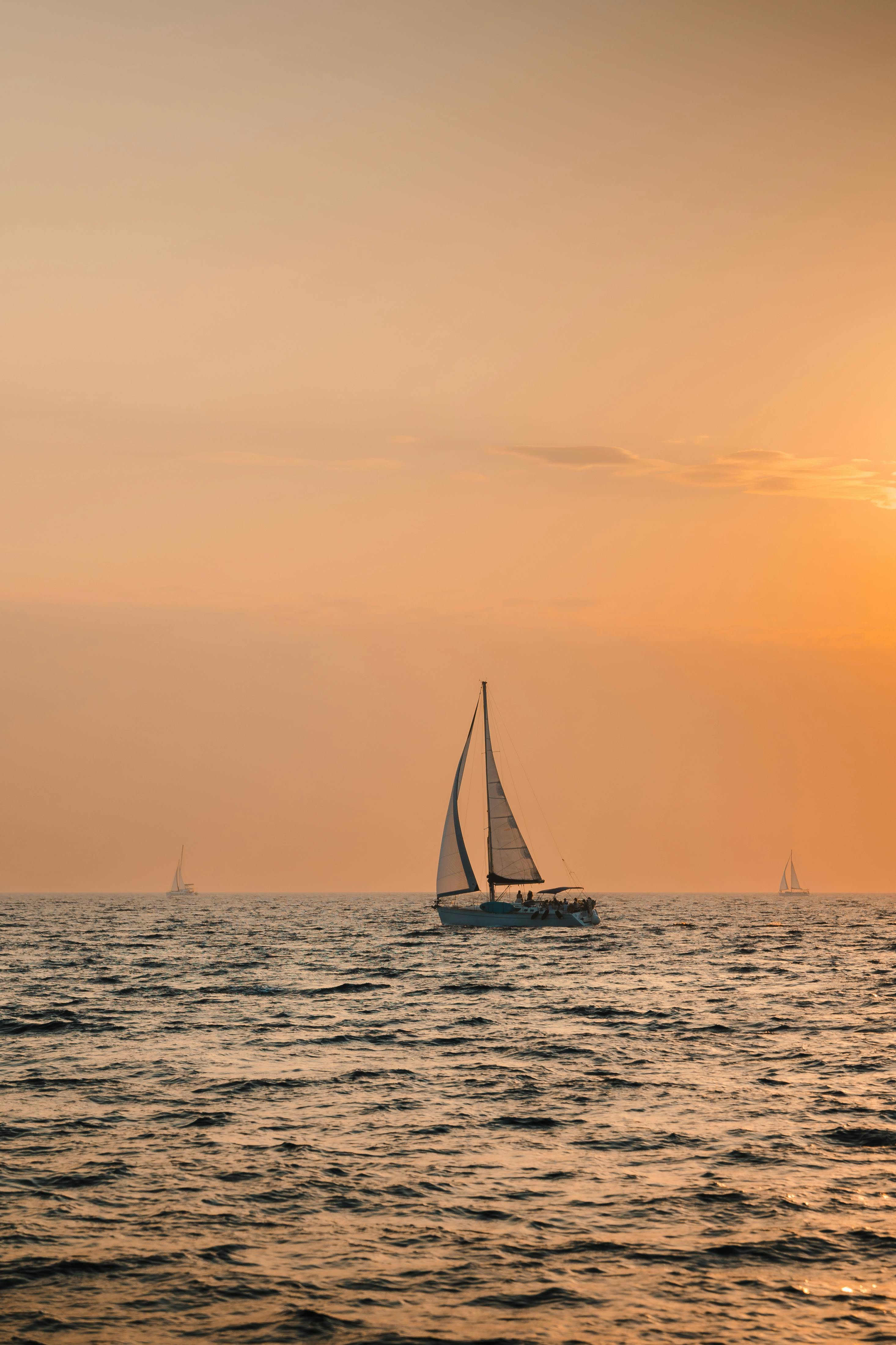 A picturesque sailboat on calm waters with a vibrant sunset backdrop, evoking tranquility.