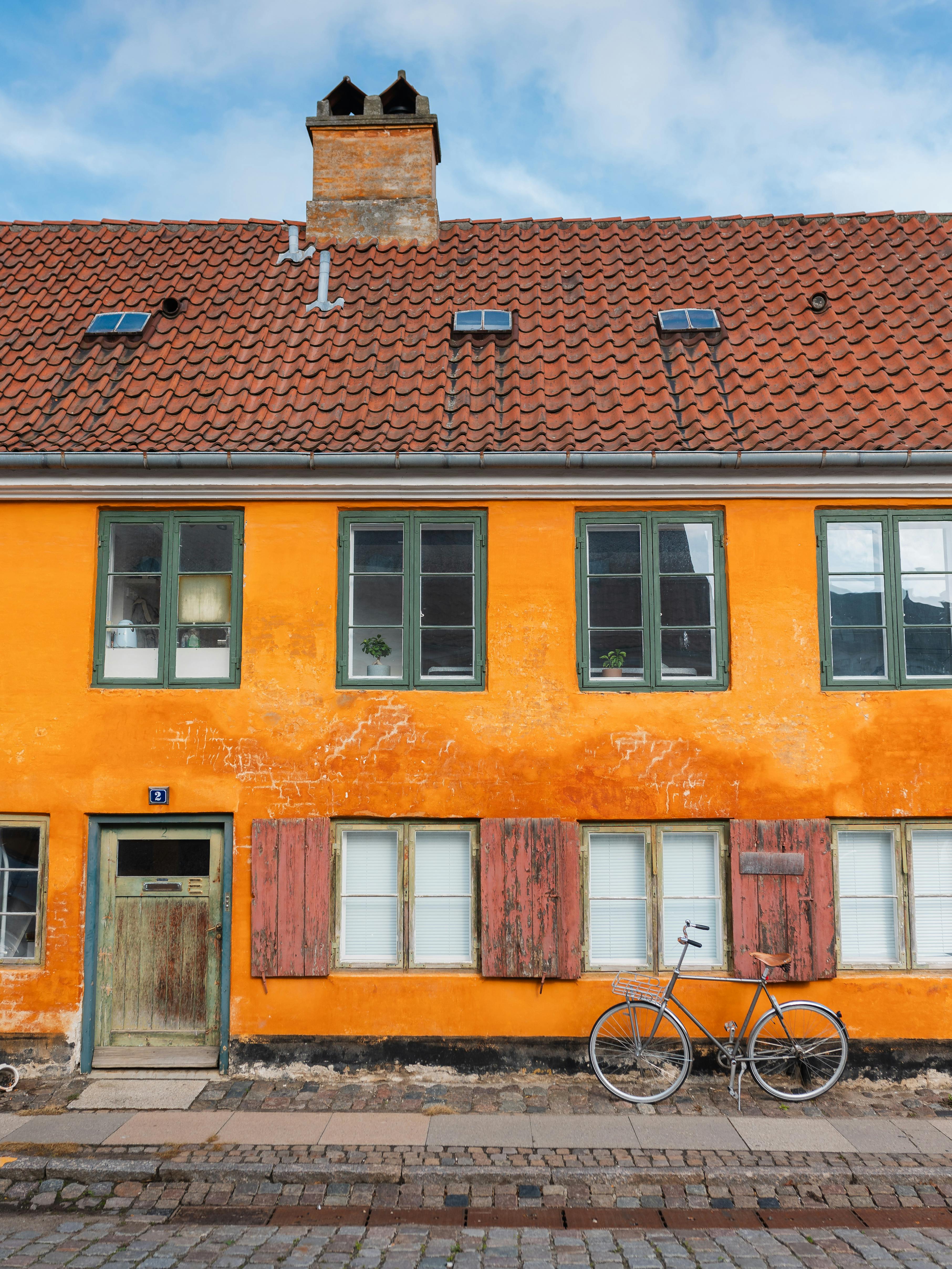 Orange building facade with a vintage bicycle parked outside, showcasing European architecture.