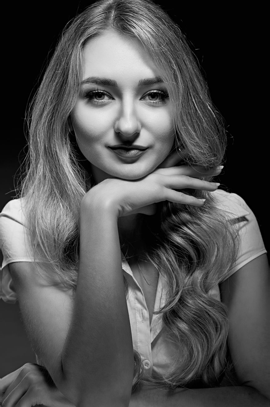 Artistic black and white photo of a woman posing in classic style, emphasizing elegance.