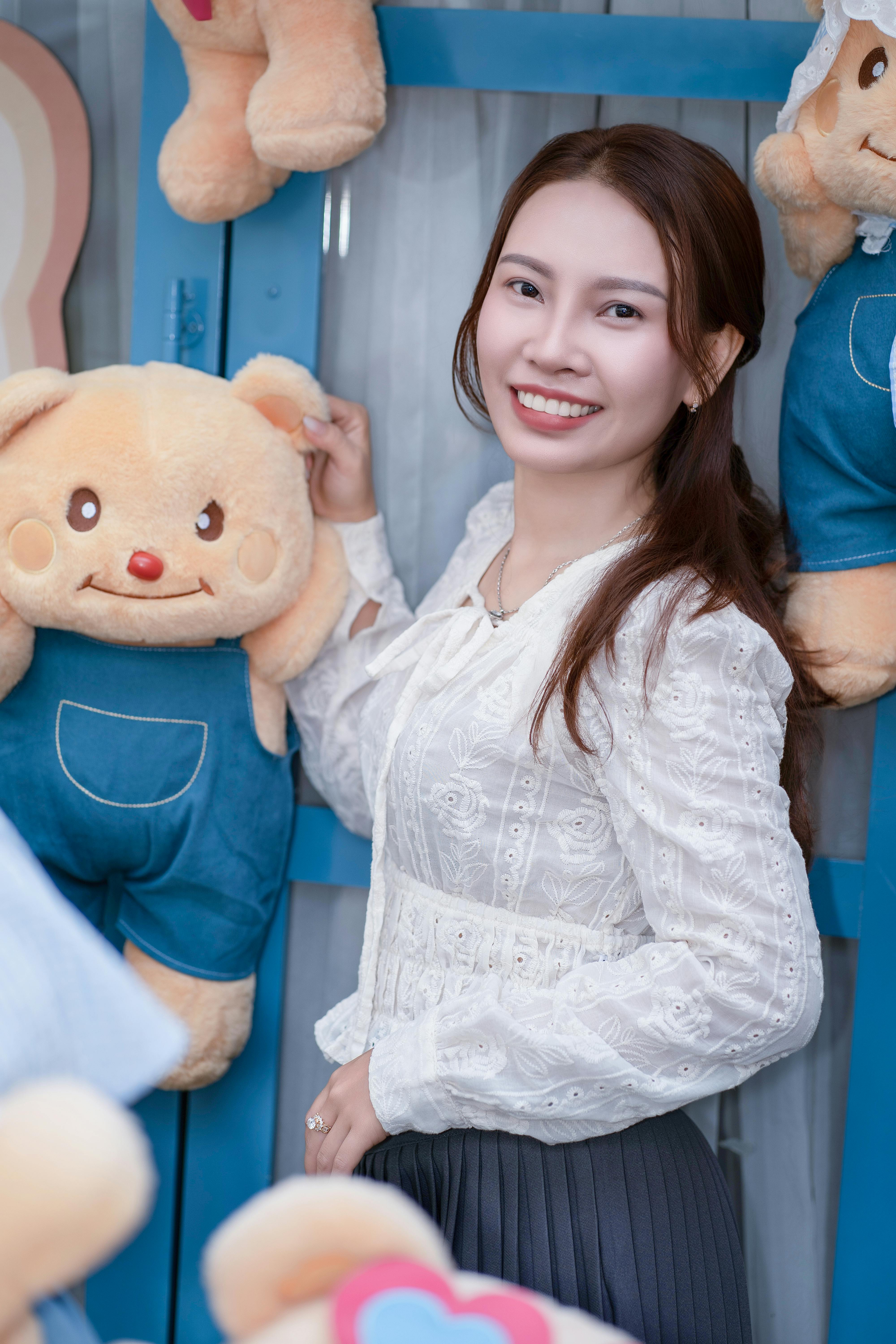 Happy woman posing with teddy bear toys, showcasing joy and playfulness.