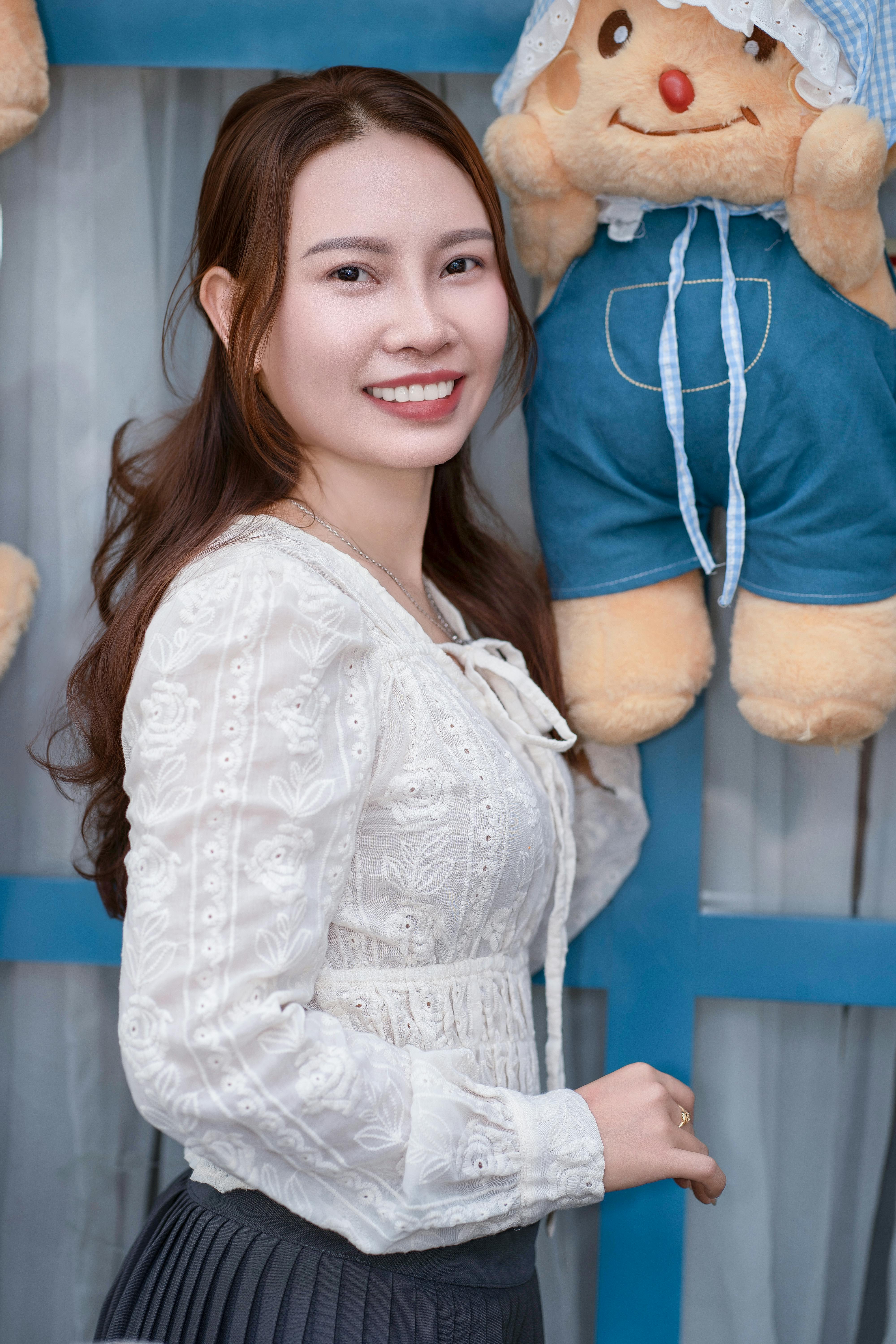Young woman smiling while holding a plush toy indoors, showcasing joy and warmth.