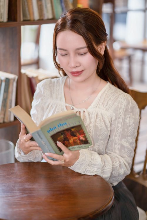 Free Young woman reading in library, enjoying leisure time with a book. Stock Photo