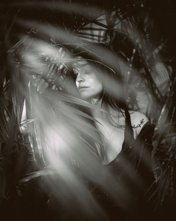 Greyscale Photography of Woman Behind Palm Leaves