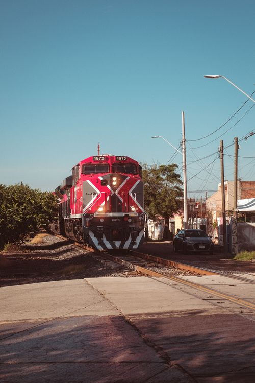 Red Train Route Red Train Passing Through Urban Railway Crossing · Free Stock Photo