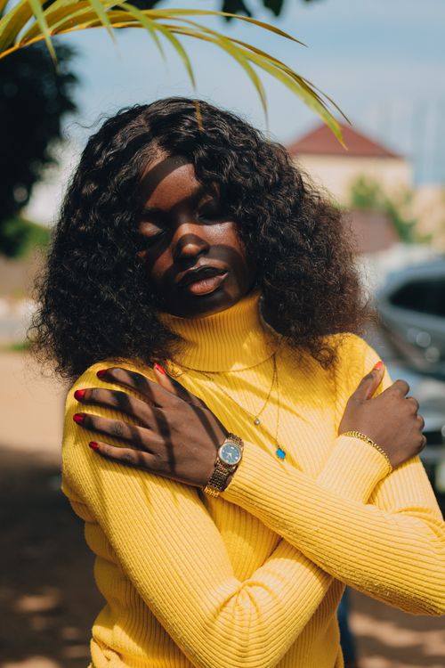 Free Portrait of a woman in a yellow sweater under sunlight, embracing peace. Stock Photo