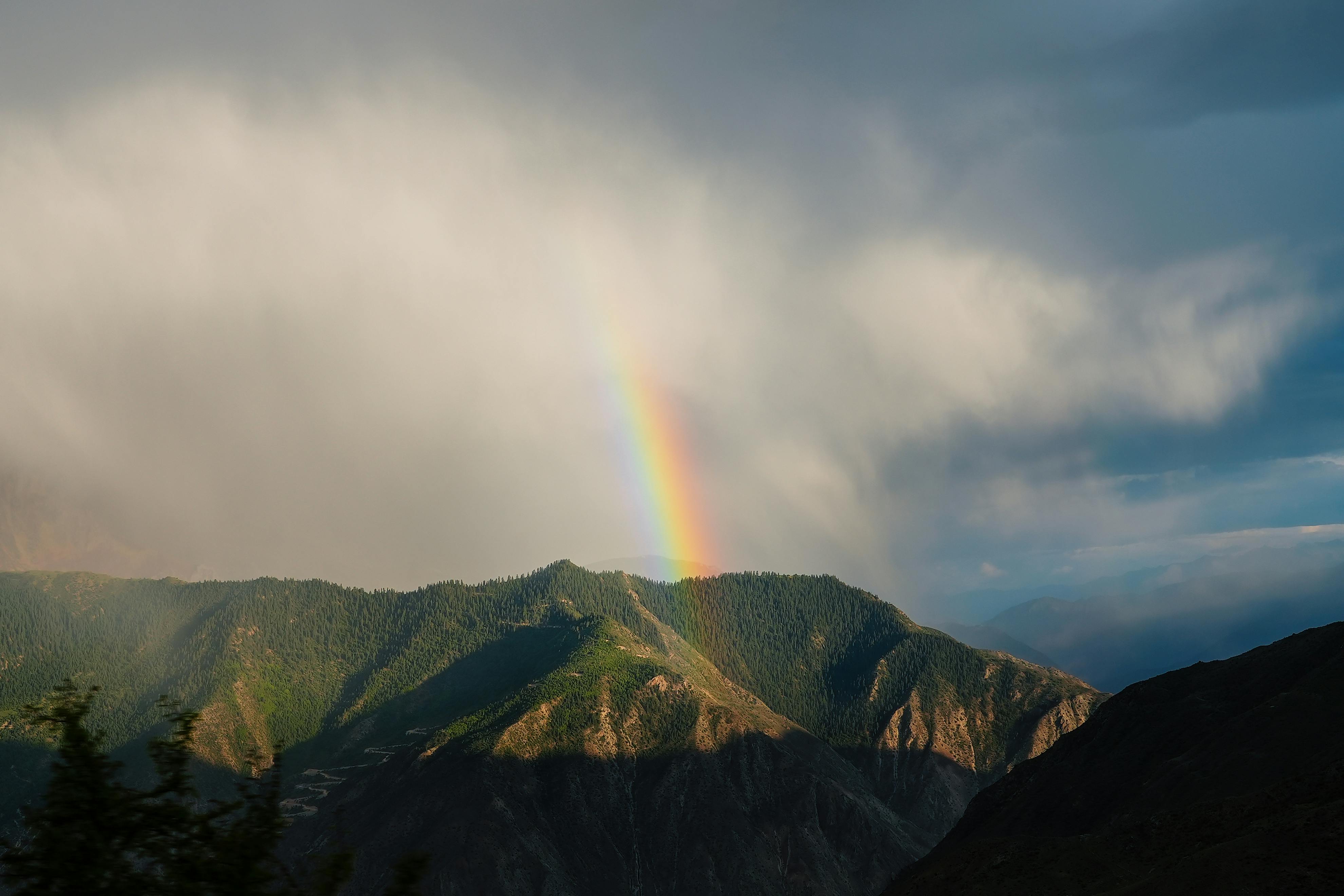 Beautiful rainbow over lush mountains in Tibet, China, capturing nature's awe-inspiring beauty.