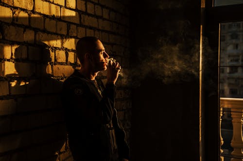 Homme Fumant Et S'appuyant Sur Le Mur De Briques