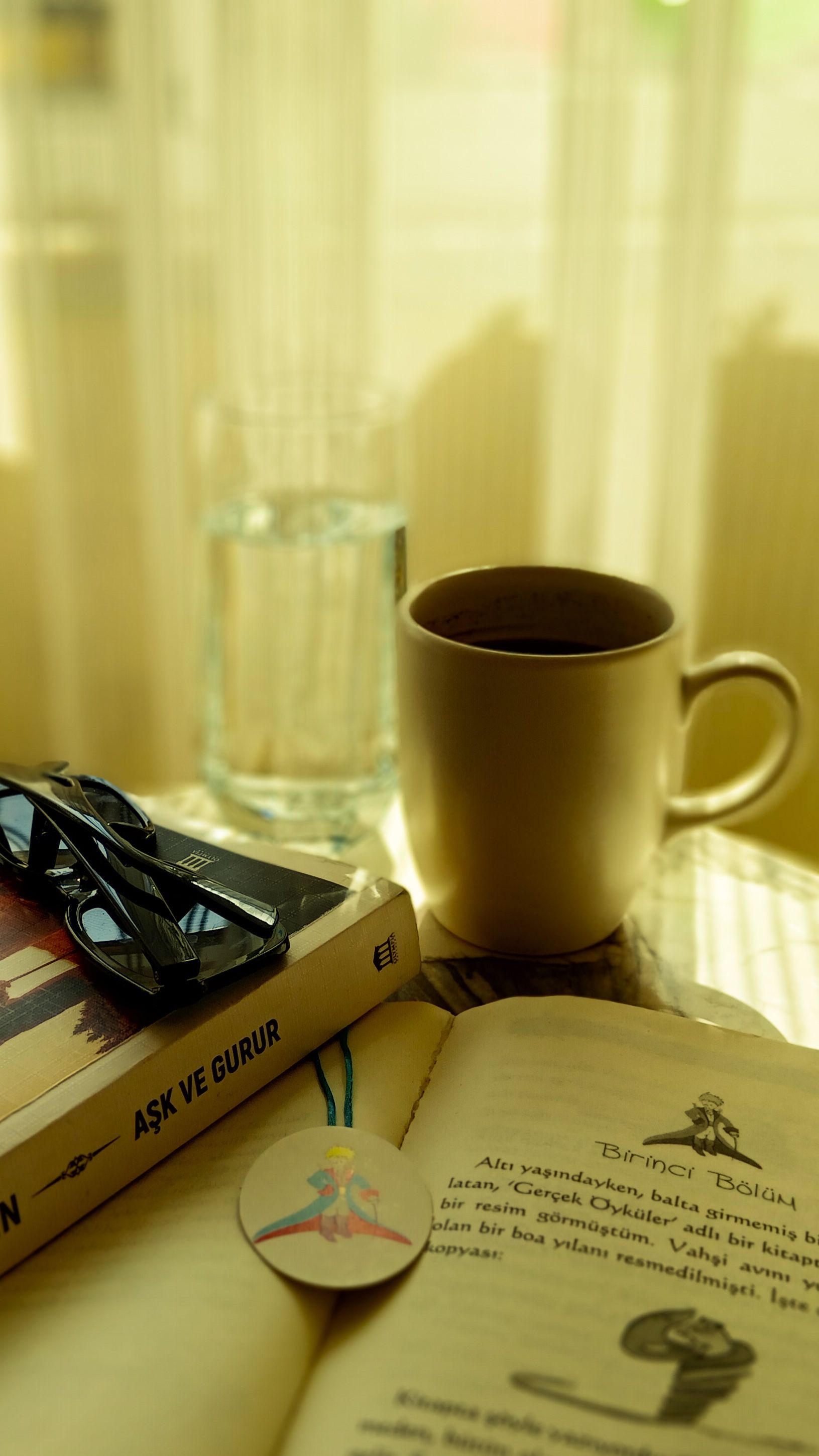Warm indoor scene with coffee, books, and glasses for a relaxing reading session.