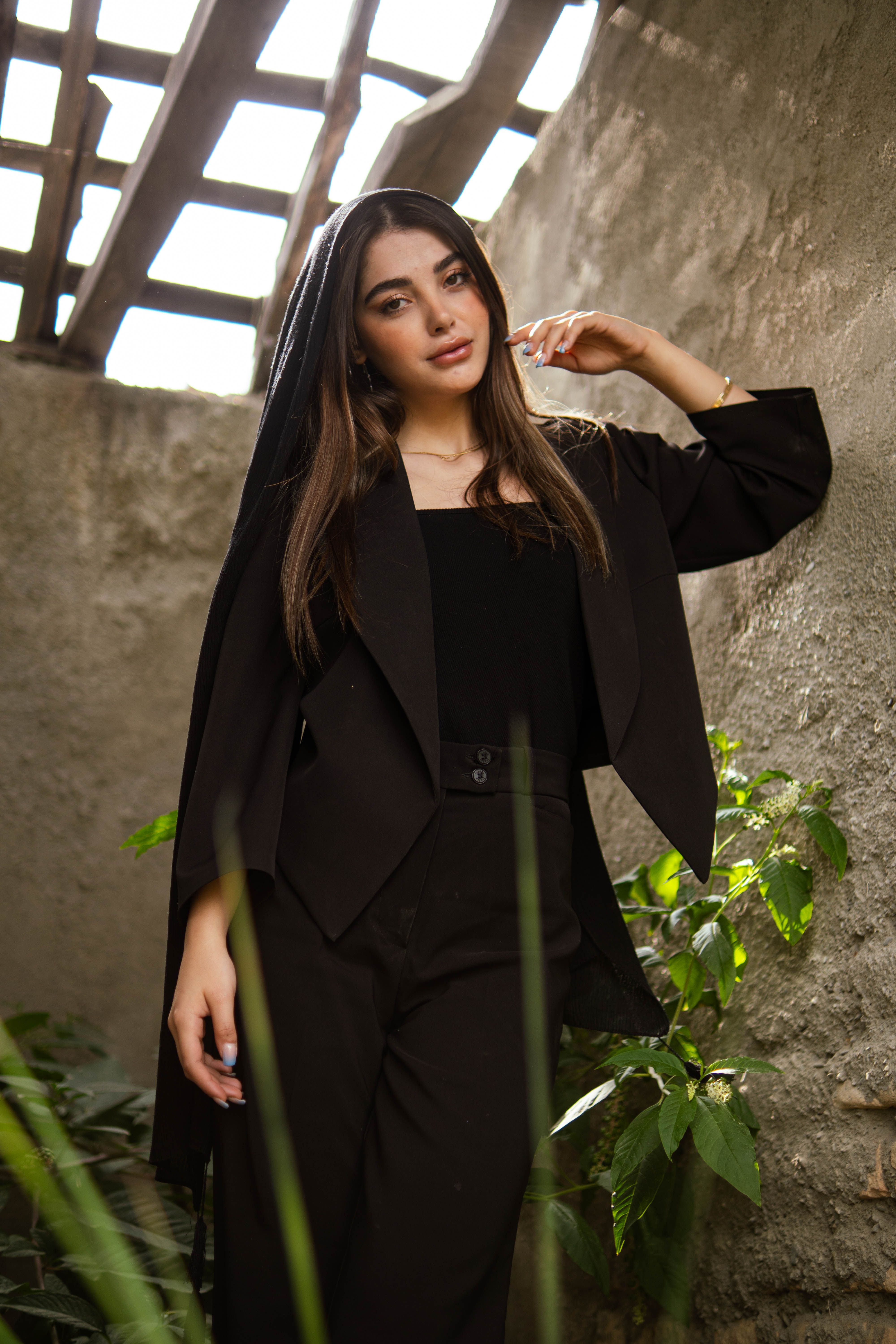 Stylish woman posing in an elegant black outfit, captured in natural lighting.