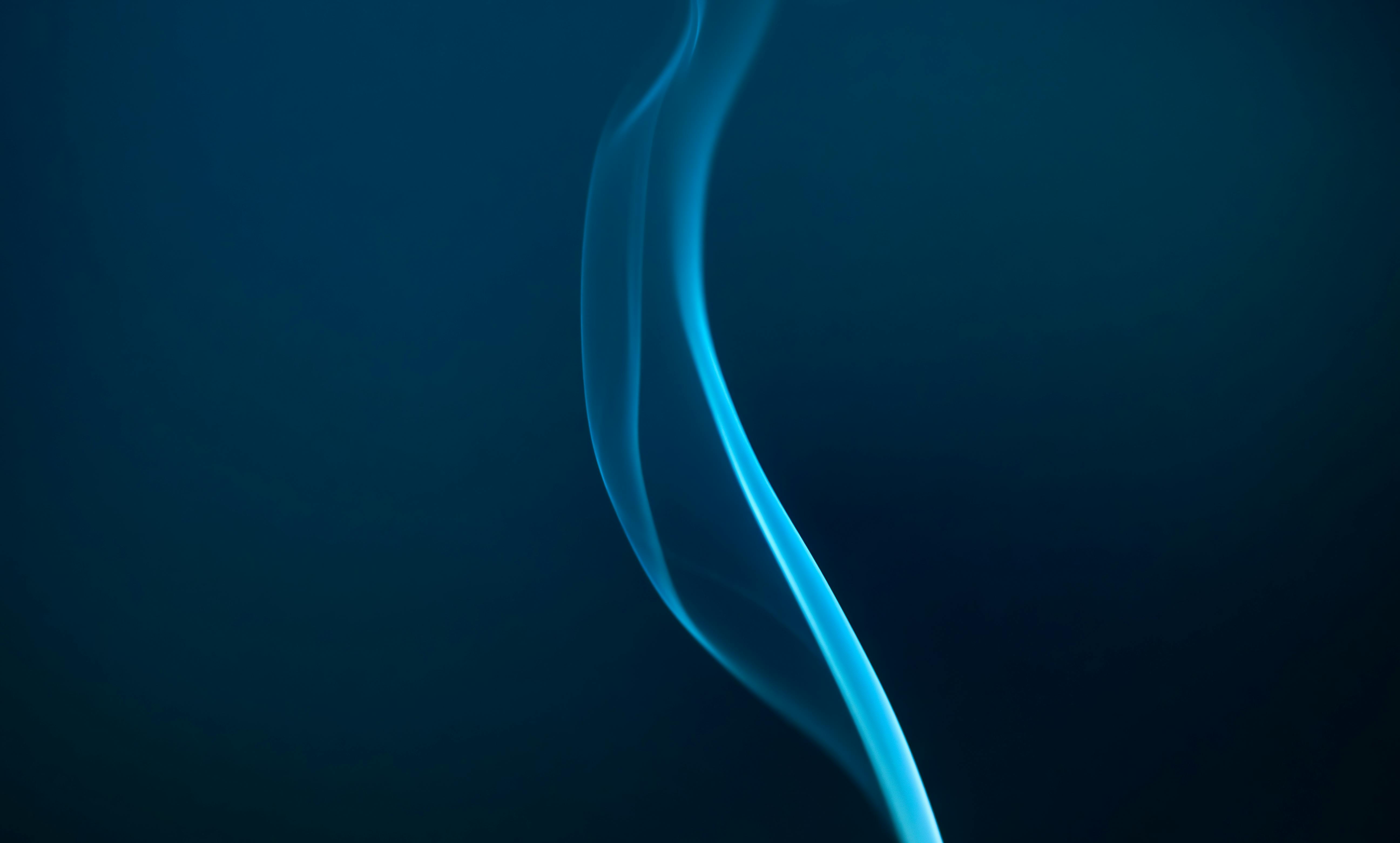 Gratis Elegante fumo blu che si muove con grazia su uno sfondo scuro, creando un'immagine astratta e rilassante. Foto a disposizione