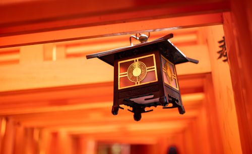 Free Close-up of a traditional lantern beneath vibrant orange torii gates in Kyoto's Fushimi Inari Shrine. Stock Photo