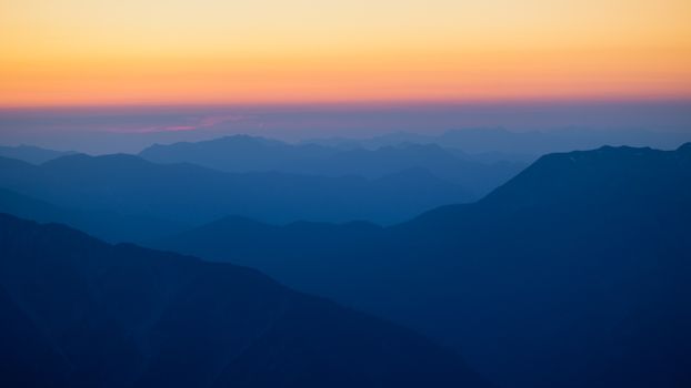 Breathtaking sunset over the layered silhouette of the Tyrolean Alps, Austria.