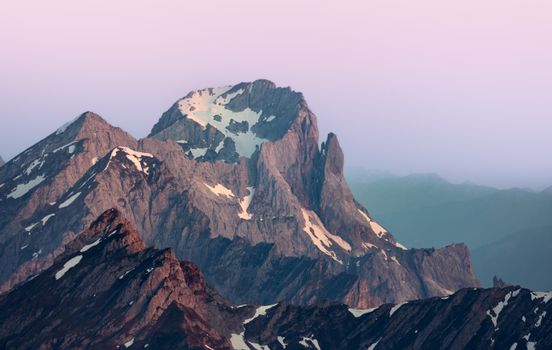 Stunning view of rugged mountain peaks with pink sunrise hues in Tyrol, Austria.