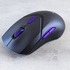 Black wireless gaming mouse with purple side buttons on a grey surface