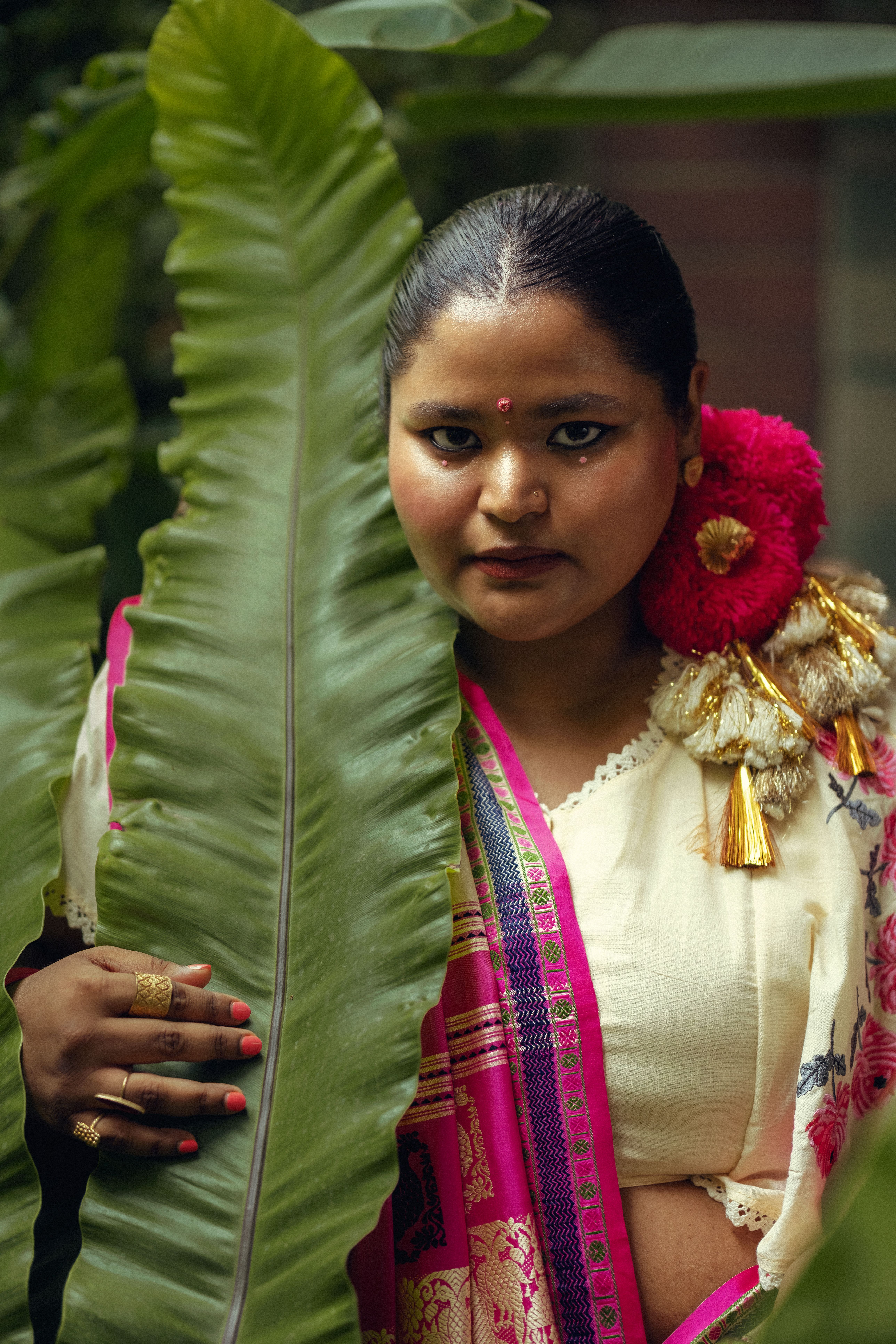 Portrait of a woman in traditional attire with tropical plant.