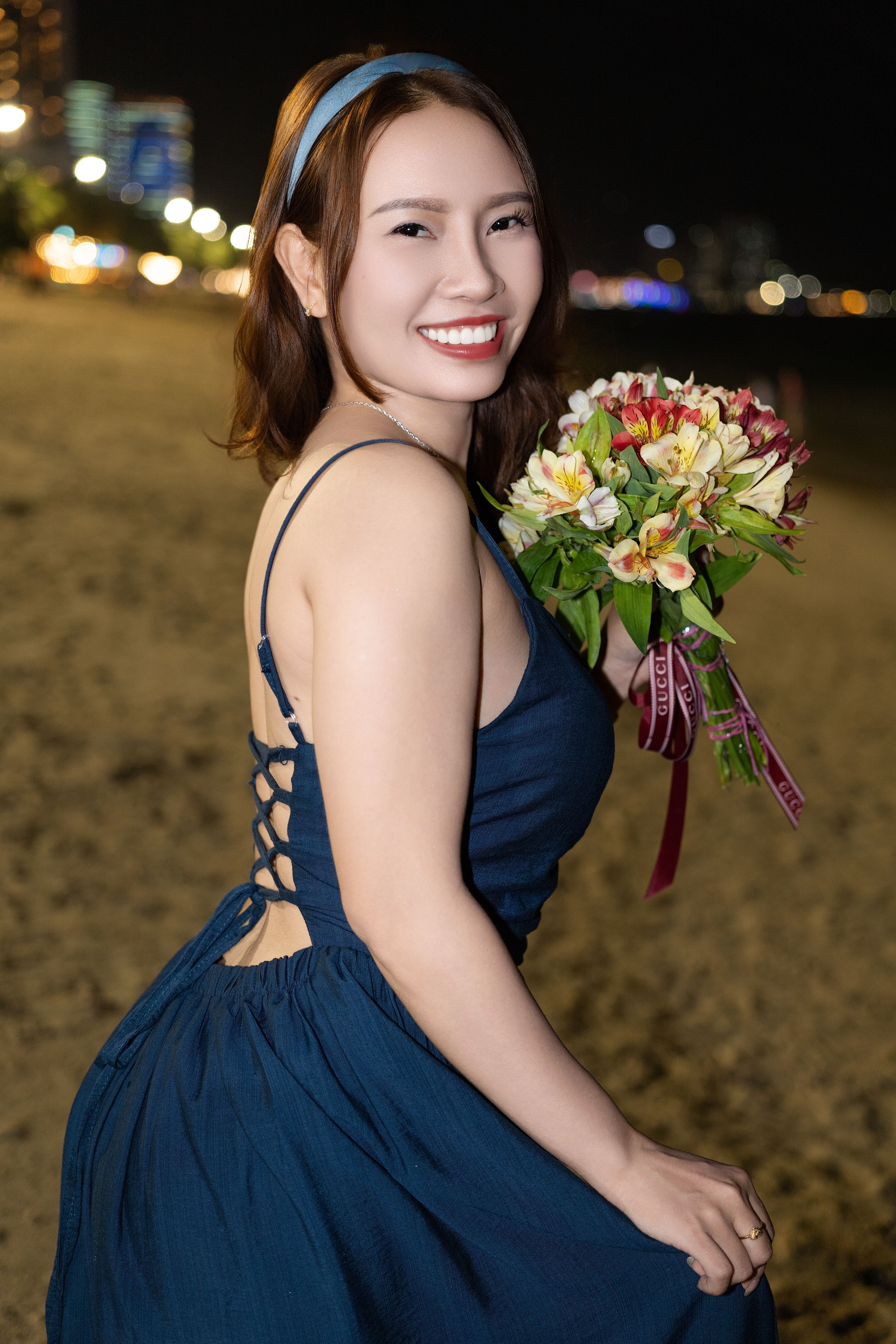 Smiling Woman Holding Bouquet on Night Beach · Free Stock Photo