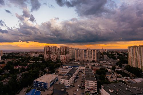 Free Aerial view of urban buildings at sunset with dramatic clouds enhancing the vibrant skyline. Stock Photo