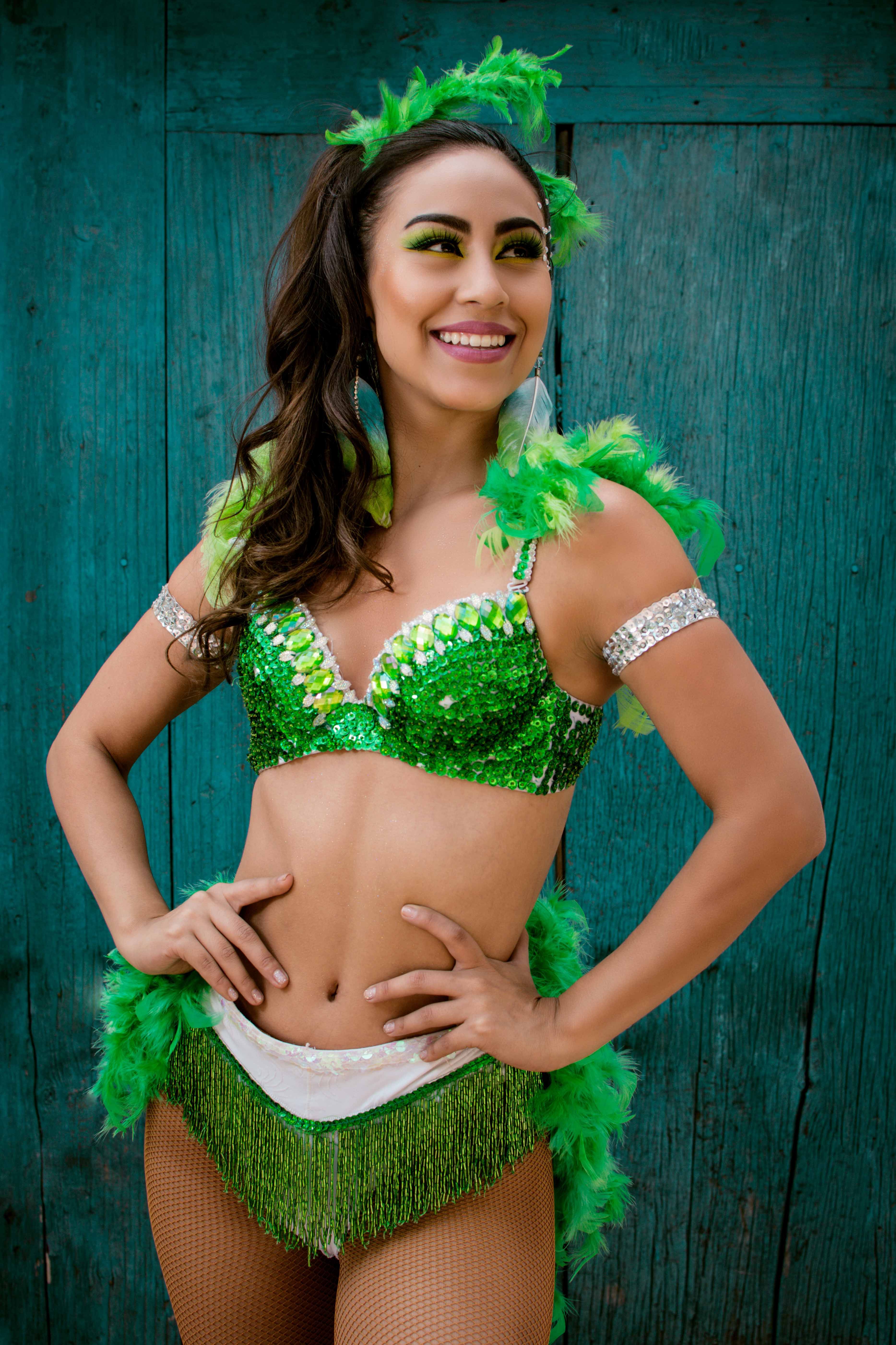 A vibrant dancer in a sparkling green costume celebrates with joy.