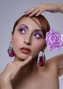 A striking portrait featuring a woman with a lavender rose and bold earrings, exuding elegance and fashion.