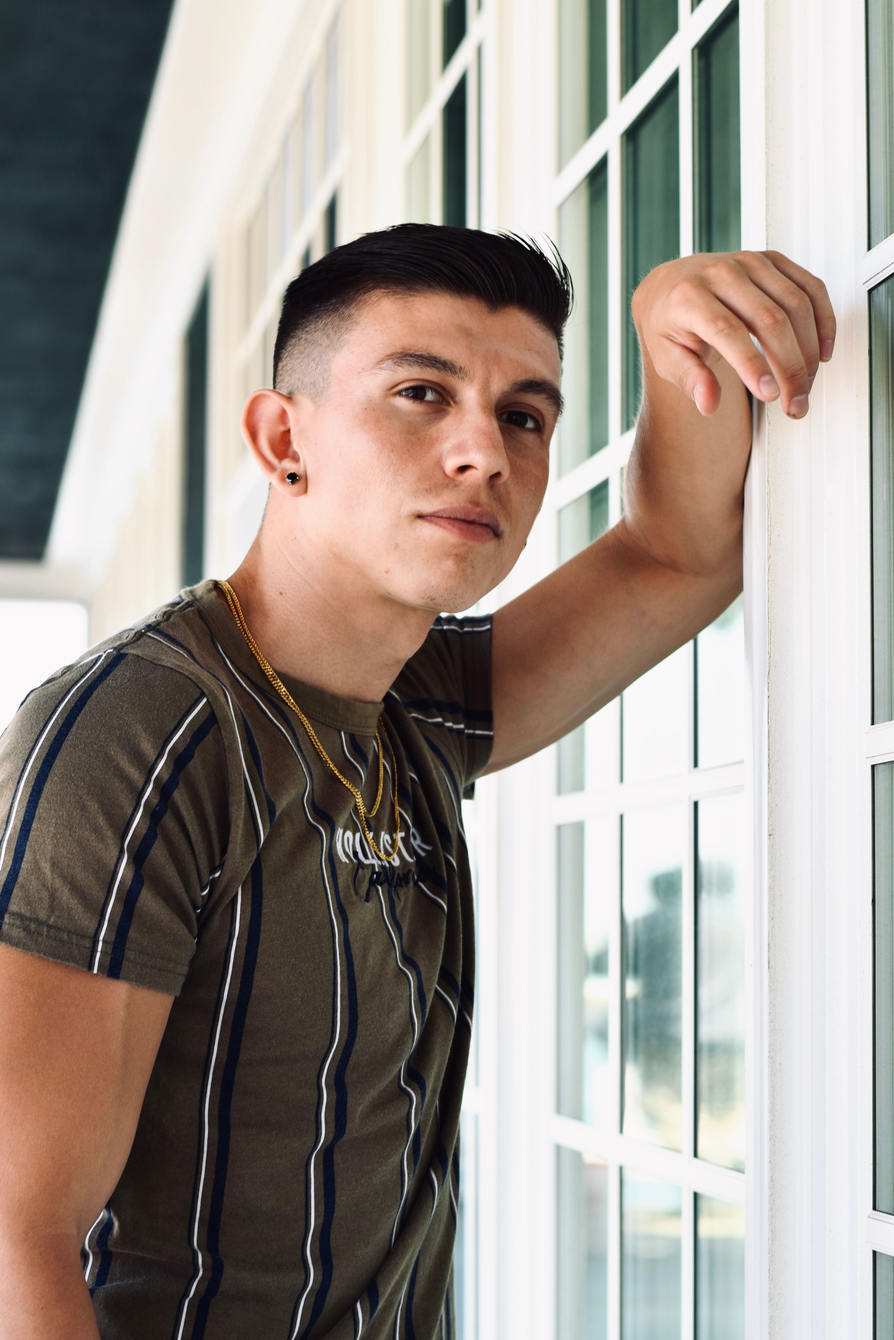 Portrait of a young man leaning against a window in California.