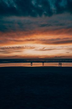 Captivating beach sunset with silhouetted figures against a dramatic sky.