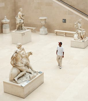 A young man explores a serene museum hall displaying classical sculptures. Artistic and contemplative atmosphere.