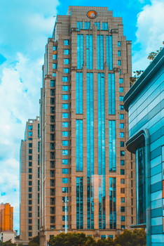 A modern skyscraper with blue windows against a bright sky in Shanghai.