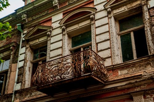 Free Close-up of a vintage European building facade with ornate, rusty balcony railing. Stock Photo
