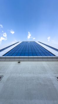 Architectural perspective of a glass skyscraper against a bright blue sky.