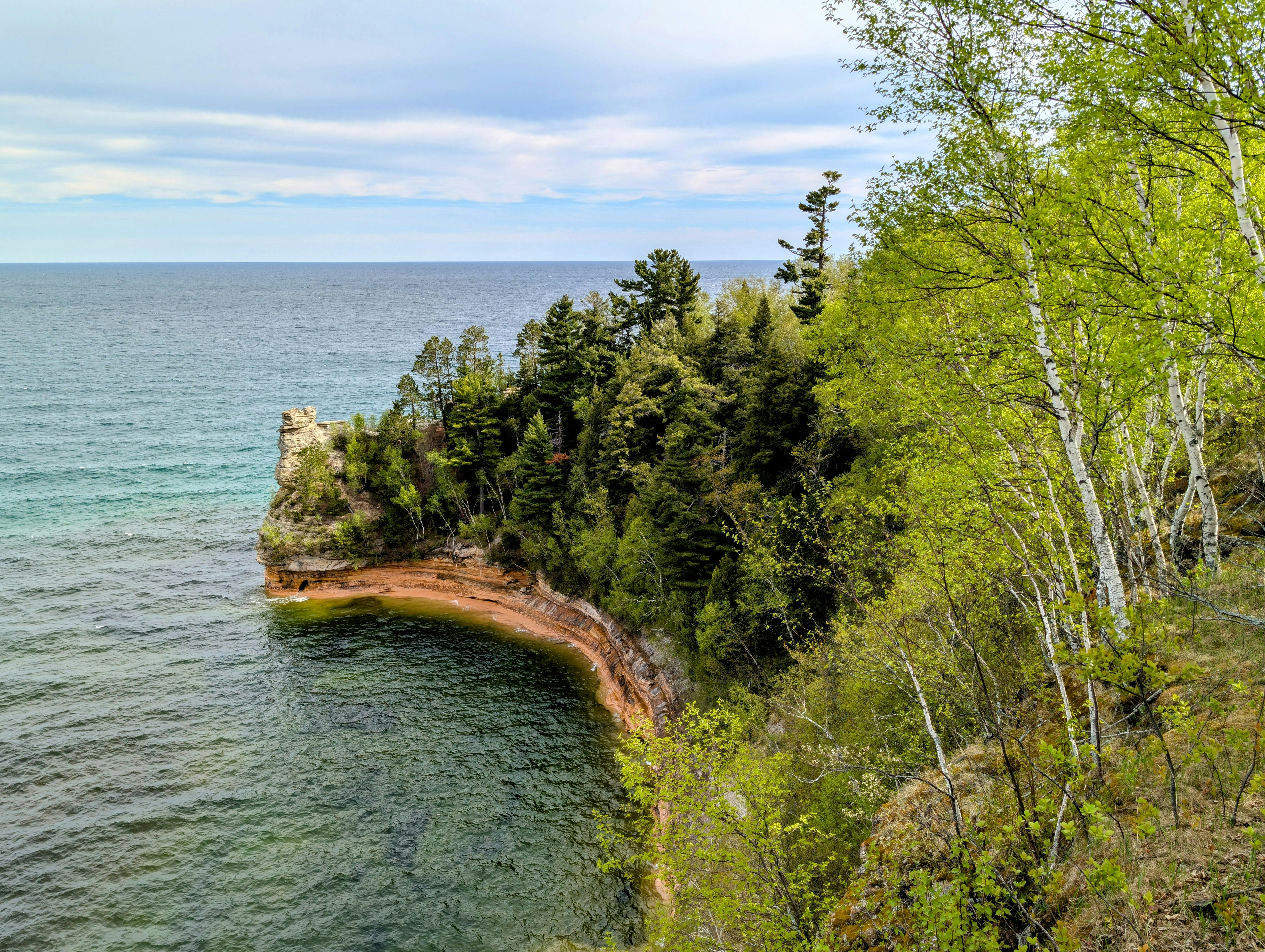 Scenic view of Pictured Rocks National Lakeshore's cliffs and vibrant spring foliage in Michigan.