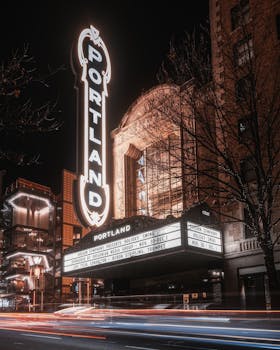 Long exposure photo of Portland theater with light trails and illuminated signage at night.