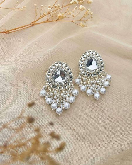Silver-tone teardrop earrings with a fringe of pearls on cream fabric
