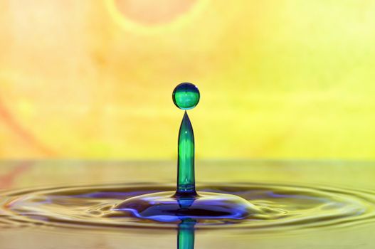 A stunning macro shot capturing a vibrant water droplet in motion, set against a colorful background.