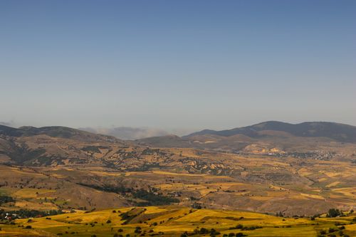Free Vast view of rolling hills and distant mountains under clear blue skies. Stock Photo