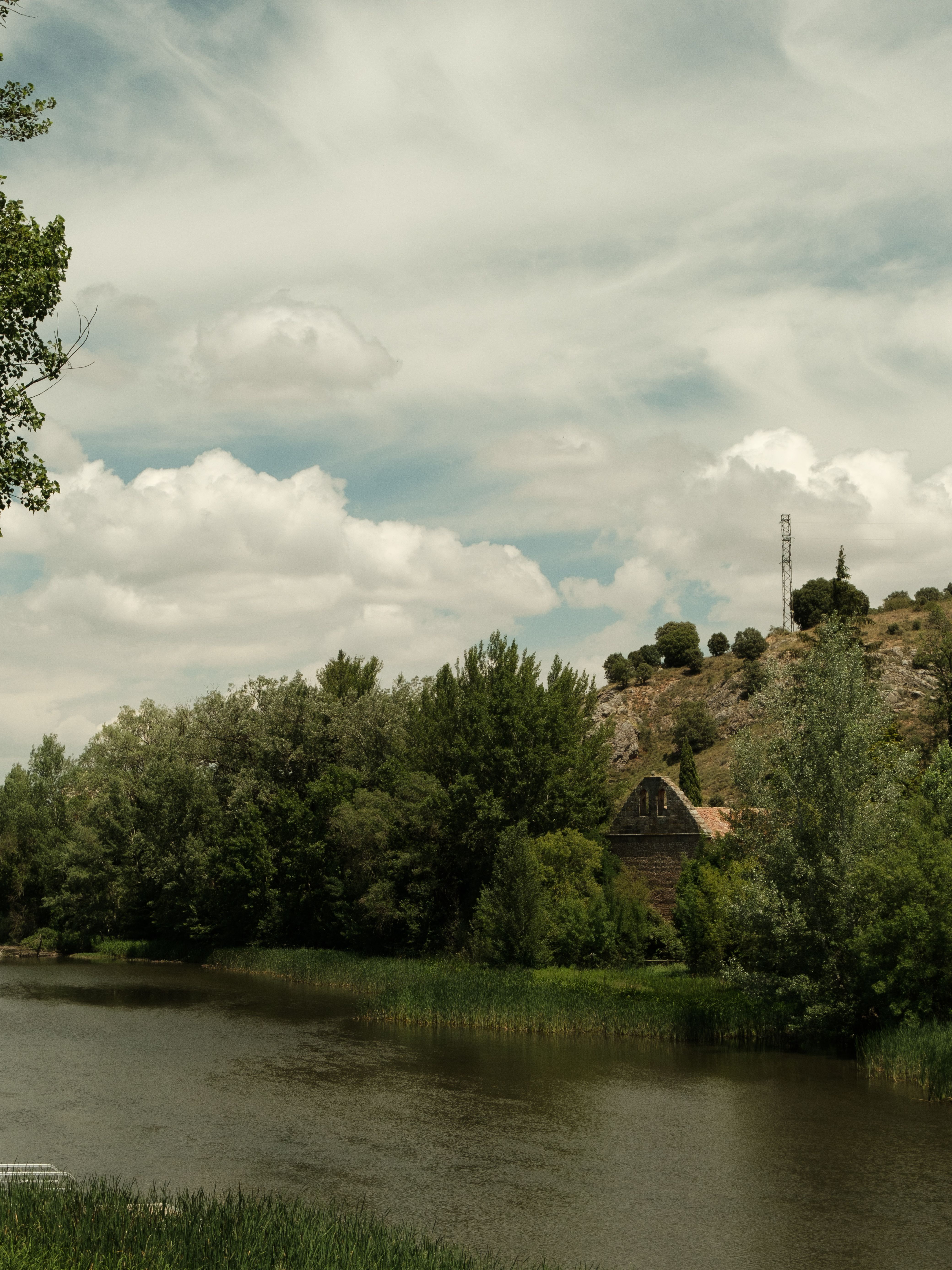 Serene River Landscape with Rustic House and Hills · Free Stock Photo