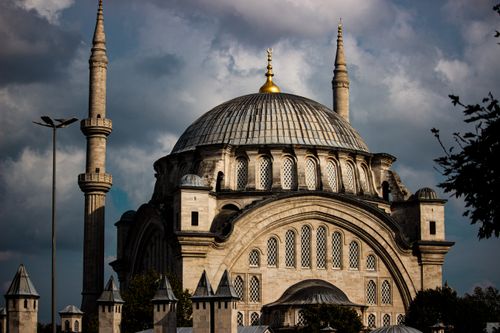 Free A stunning architectural mosque with a dome and minarets under a dramatic cloudy sky. Stock Photo