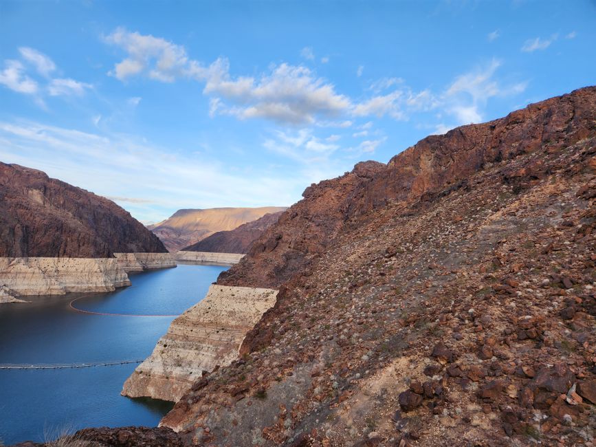 Breathtaking landscape of Colorado River and rugged cliffs near Hoover Dam, captured under a bright blue sky.