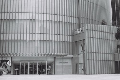 Free Contemporary building facade with luxury boutique entrances under a sleek metallic design. Stock Photo
