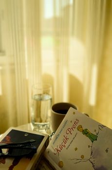 Serene indoor scene with 'Little Prince' book, coffee, and natural light.