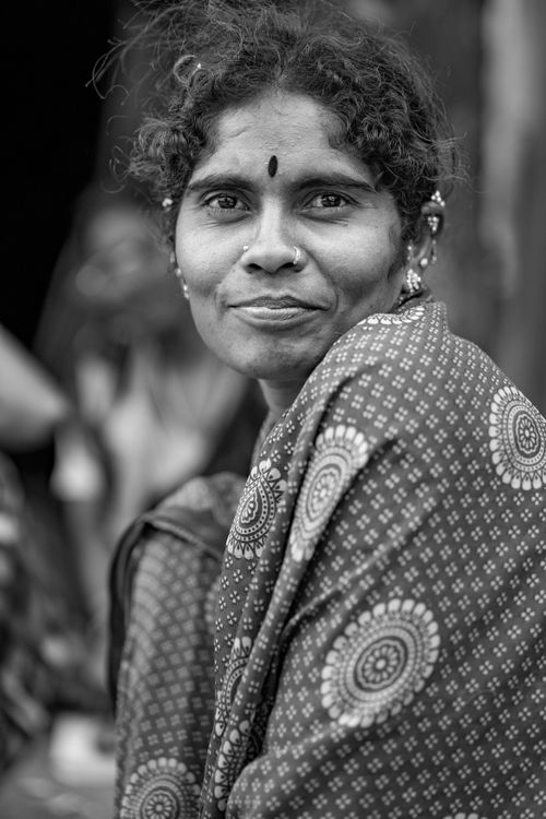 Free Black and white portrait of a woman wearing traditional attire with a warm smile, captured outdoors. Stock Photo