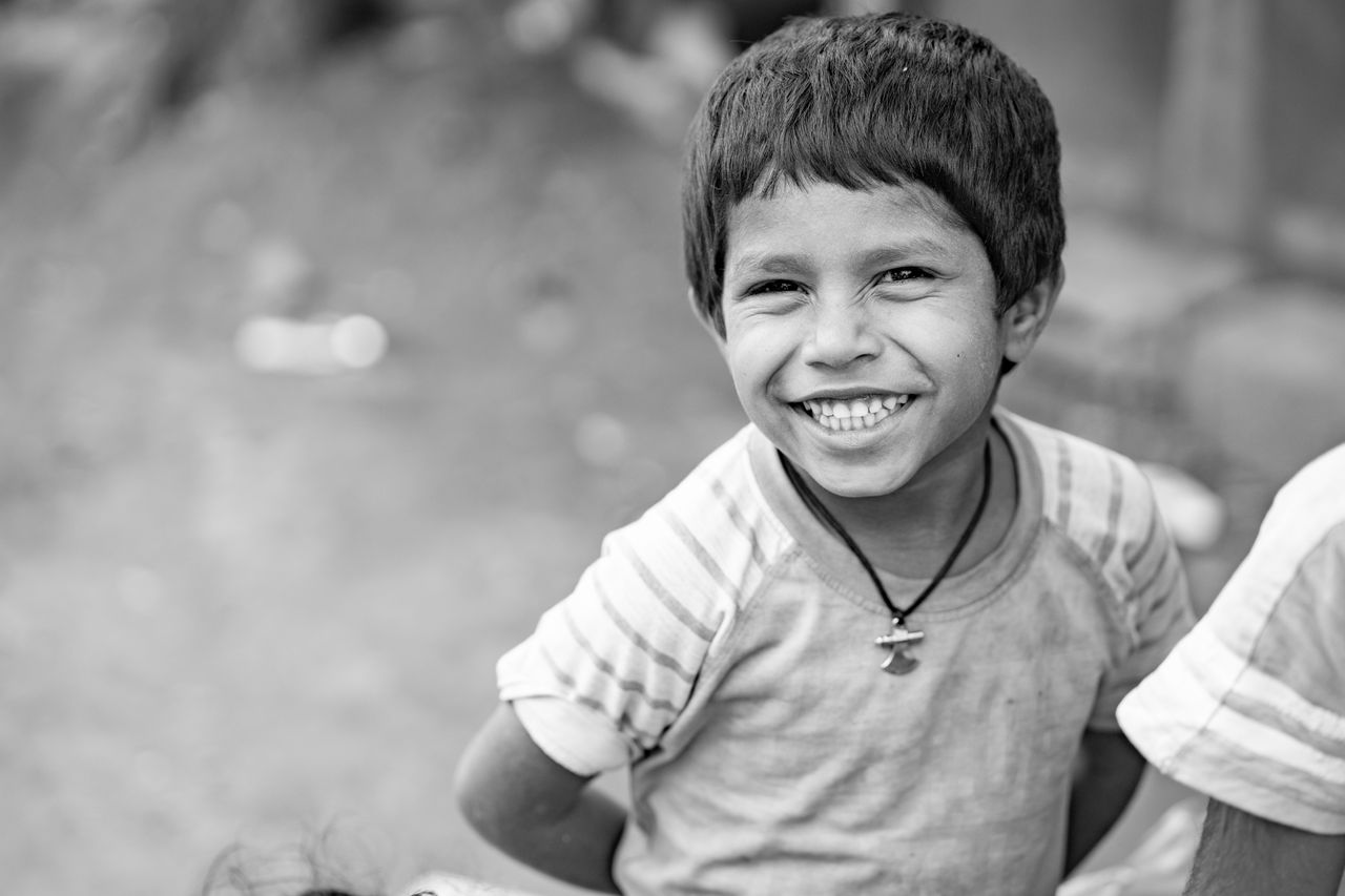 black and white portrait of a smiling child in a casual setting expres