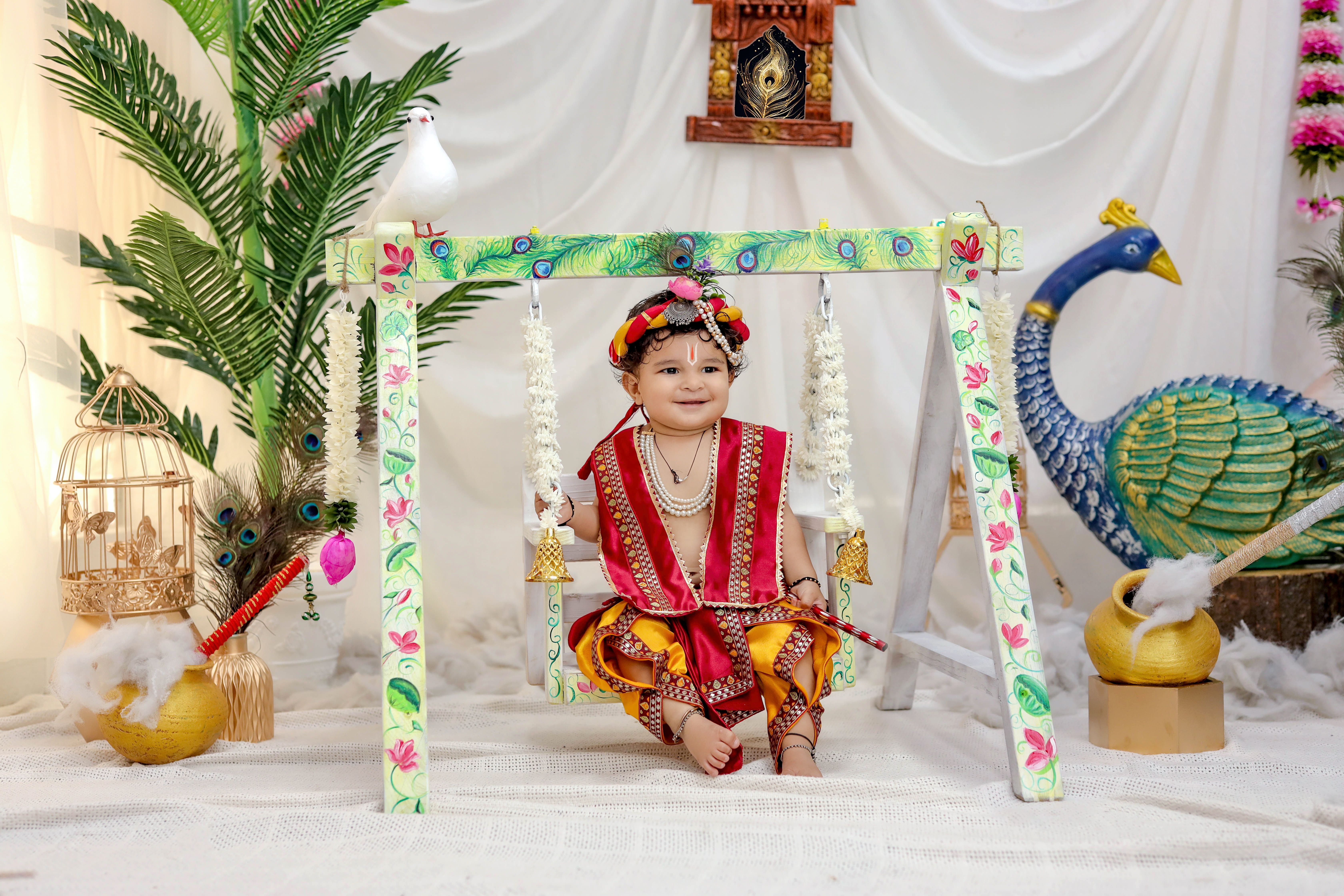 Happy child dressed as Krishna on a beautifully decorated swing indoors.
