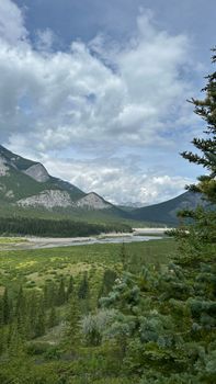 Beautiful mountain valley with lush greenery and cloudy sky, offering a serene view in summer.